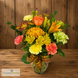 Mixed bouquet in a glass vase with orange, yellow, and pink flowers