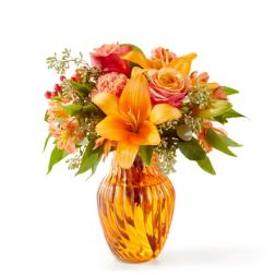 Orange and pink mixed flowers arranged in an amber glass vase