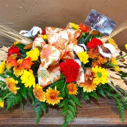 Autumn floral arrangement with yellow and red flowers and a leaf-patterned bow