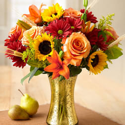 Mixed bouquet of roses, sunflowers, and lilies in a gold vase