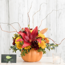 Pumpkin-shaped vase with red lilies and yellow mums