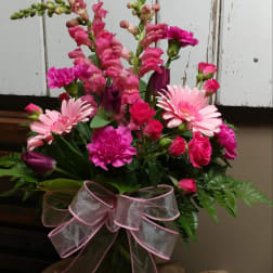 Pink mixed flower bouquet in a glass vase with a sheer ribbon bow