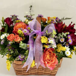 Mixed flower basket with orange roses, daisies, and a purple ribbon