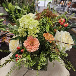 Low mixed arrangement with peach blooms, white roses, hydrangea, and berries in a square glass vase