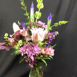 Mixed bouquet of pink, purple, and white flowers in a glass vase
