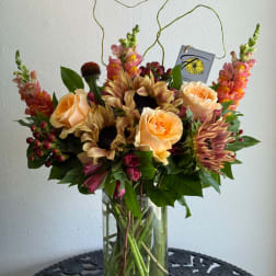 Peach roses and sunflowers in a clear glass vase