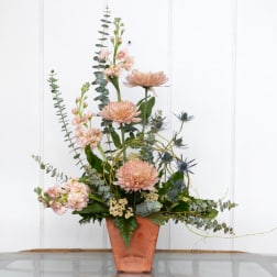 Tall floral arrangement in a copper vase with blush and blue blooms