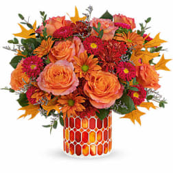 Orange roses and mums in a mosaic vase with autumn leaf accents