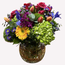 Mixed bouquet of roses, hydrangea, and daisies in a glass vase
