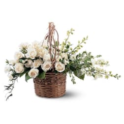 White rose arrangement in a wicker basket with trailing greenery