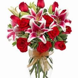 Bouquet of red roses and pink lilies in a clear glass vase