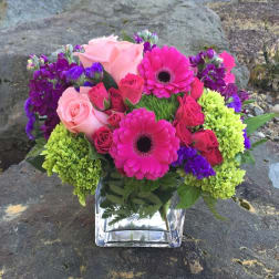 Pink and purple mixed bouquet in a clear square vase