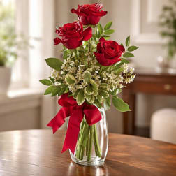 Red roses in a clear glass vase with a red ribbon