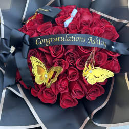 Red rose bouquet with a graduation cap and black ribbon reading Congratulations Ashley