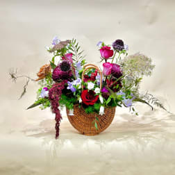 Mixed flower arrangement in a wicker basket with red and pink roses
