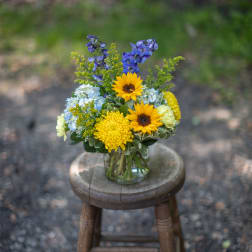 Mixed bouquet in a clear glass vase with yellow sunflowers and blue flowers