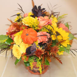 Autumn floral arrangement in an orange vase with yellow and peach blooms