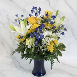 Blue and yellow mixed bouquet in a dark vase