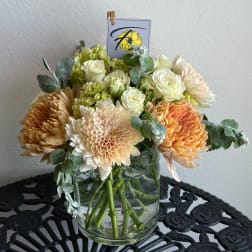 Peach and white flowers arranged in a clear glass vase