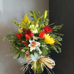 Mixed bouquet of red, yellow, and white flowers in a glass vase