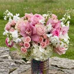 Pink roses and orchids arranged in a vase with white flowers