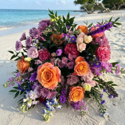 Large bouquet of orange, pink, and purple flowers on a beach