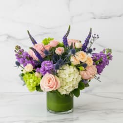 Bouquet of pink and cream roses with purple flowers in a green vase