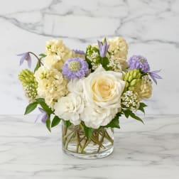 White and lavender flowers arranged in a clear glass vase