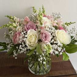 Pink and white roses with baby's breath in a clear glass vase