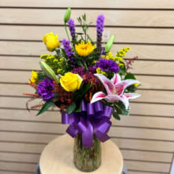 Mixed bouquet in a glass vase with a purple ribbon and lilies