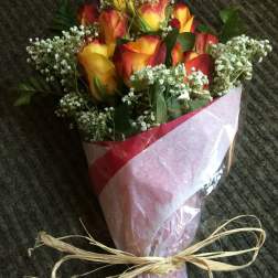 Bouquet of red and yellow roses wrapped in pink paper