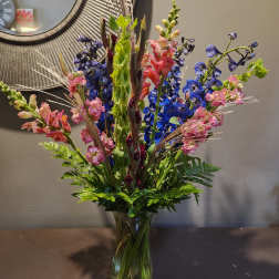 Tall mixed bouquet in a glass vase with blue and pink flowers