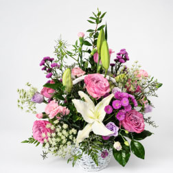 Pink and white mixed flower arrangement in a white basket