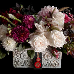 Mixed bouquet of white roses and magenta blooms in an ornate rectangular container