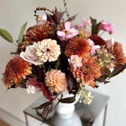 Bouquet of orange, pink, and cream flowers in a white vase