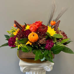 Autumn floral arrangement with chrysanthemums and small pumpkins in a wooden container