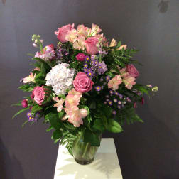 Pink roses and mixed flowers arranged in a clear glass vase
