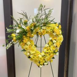 Yellow and white floral heart wreath on a stand
