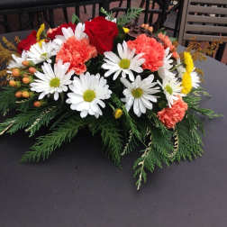 Low floral centerpiece with red roses, white daisies, and coral carnations