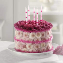 Round floral cake with pink candles on a white plate