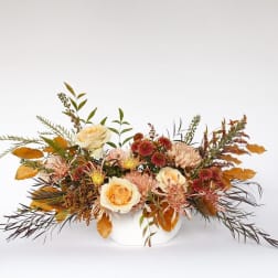 Autumn floral arrangement in a white vase with cream roses and mums