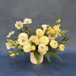 Cream and yellow floral arrangement in a white vase