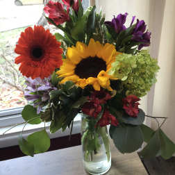 Mixed bouquet with sunflowers, gerbera daisies, and alstroemeria in a glass vase