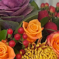 Close-up of orange roses, yellow chrysanthemum, purple ornamental cabbage, and red berries.