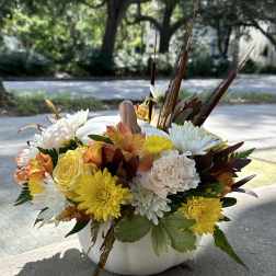 Autumn floral arrangement in a white pumpkin vase with yellow, white, and peach blooms