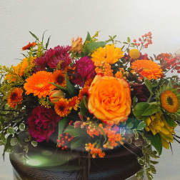 Bright mixed bouquet with orange and magenta flowers in a dark vase