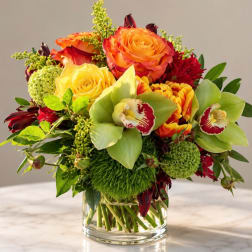 Mixed bouquet of orange and yellow roses with green orchids in a glass vase