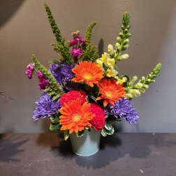 Colorful mixed flower arrangement in a pale green vase