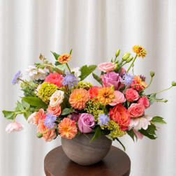 Colorful mixed flower arrangement in a gray vase on a round table