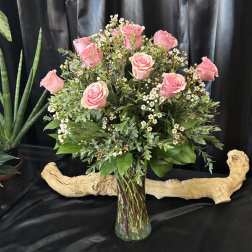 Pink roses arranged in a clear glass vase with small white filler flowers.